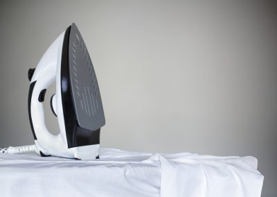 Ironing a white shirt with a steam iron on an ironing board